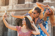 Three happy young women friends tourists taking selfies at Colosseum in Rome, Italy at sunrise.