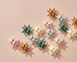 © Yaroslav Danylchenko/Stocksy - Holiday composition of different paper origami stars on a beige background with copy space. Layout for the new year or Christmas. Flat lay