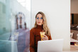 © Javier Pardina/Stocksy - Woman with autumn outfit working inside coffee bar.