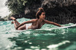 © Olga Sinenko/Stocksy - Young indonesian woman on a surf board in the ocean