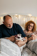 © Brat Co./Stocksy - Senior Couple in bed with their Dog