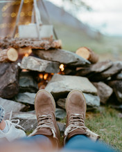 Girl's Legs In Boots Of A Fire With A Bowler Hat On Nature On The Background