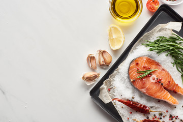 Wall Mural - top view of uncooked salmon steak with lemon, rosemary and chili peppers on oven tray with salt