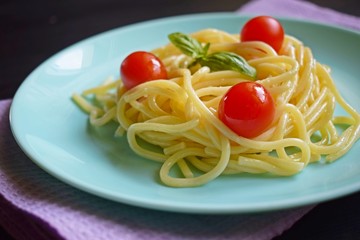 Wall Mural - Delicious spaghetti with herbs and tomatoes on a black background.