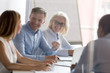 © fizkes - Smiling employees brainstorm sharing ideas at briefing