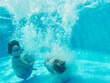 © Indico Studio/ADDICTIVE STOCK - Cheerful playful boys jumping deep inside of clear pool water having fun