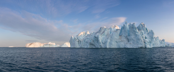 Wall Mural - Icebergs in front of the fishing town Ilulissat in Greenland. Nature and landscapes of Greenland. Travel on the vessel among ices. Phenomenon of global warming. Ices of unusual forms and colors. 