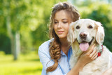 Fototapeta Zwierzęta - Young woman with golden retriever dog in the summer park