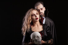Portrait Of Vampire Couple Posing For Halloween Against A Black Background