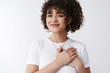 © Cookie Studio - My heart skips beat. Attractive glad tender curly-haired brunette mixed-race girl hold hands pressed chest grateful smiling happy touched receive awesome surprise gift thankful, appreciate