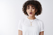 © Cookie Studio - Oh wow. Entertained impressed silly attractive curly hairstyle mixed-race lesbian girl look surprised open mouth astonished smiling glad hear good amusing news, standing white background