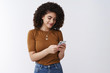 © Cookie Studio - Stylish modern girl checking mailbox holding smartphone look phone screen display smiling delighted messaging writing post social media page scroll feed app standing white background
