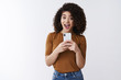 © Cookie Studio - Say cheese. Cheerful attractive amused happy curly-haired girlfriend holding smartphone taking picte friend asking smile make selfie mirror excited standing white background upbeat