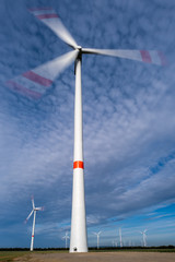 Wall Mural - Windkraftanlage mit Langzeitbelichtung, leicht bewölkter blauer Himmel im Hintergrund