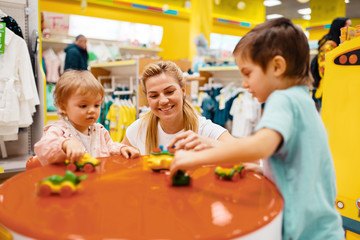 Wall Mural - Mother with little children playing in kids store