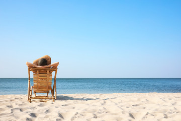 Poster - Young woman relaxing in deck chair on sandy beach