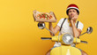 Photo of serious dissatisfied busy pizza man shows tasty junk food on cardboard box, poses on fast transport, wears helmet and white t shirt, being tired of transporting food for customers. Delivery