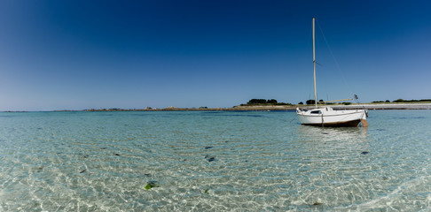 Canvas Print - panorama ocean coast and beach landscape with small sailboat under a blue sky