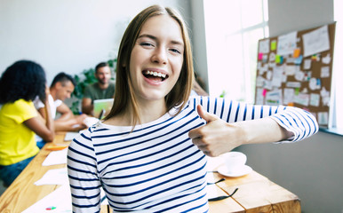 Wall Mural - Attractive confident modern business woman in casual clothes looks at the camera and smiling. Modern start-up business team. Co-workers or students 