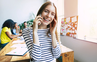 Wall Mural - Attractive confident modern business woman in casual clothes looks at the camera and smiling. Modern start-up business team. Co-workers or students 