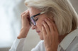 © fizkes - Stressed aged woman in glasses suffering from headache