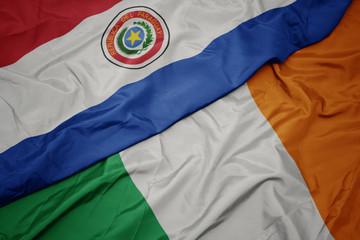 waving colorful flag of ireland and national flag of paraguay.