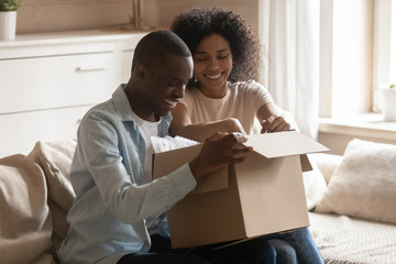 Excited biracial client couple unpack delivery box