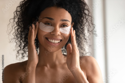 Cuadros en Lienzo Close up of smiling biracial woman apply under-eye patches