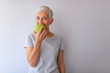 © Dragana Gordic - Portrait of happy mature woman holding granny smith apple at home. Beautiful senior woman over grunge grey wall eating green apple with happy face smiling.