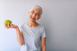 © Dragana Gordic - Portrait of a beautiful elderly woman holding an apple, smiling, isolated on gray background. Happy Woman Holding Granny Smith Apple. An aple a day keeps doctor away