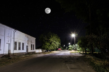 Wall Mural - full moon over quite village at night. beautiful night landscape of old town street with lights. rus