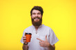 © Vulp - Happy bearded guy pointing at cup, standing over yellow background