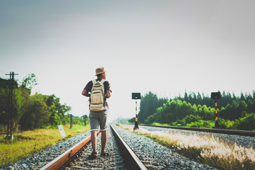 man with backpack walking away on railroad and emphasize to patience and survey trying step forward to goal. copy space