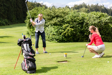 Wall Mural - Male golfer putting golf ball on the green golf