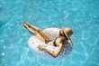 © rh2010 - Woman in swimsuit and hat swimming with inflatable ring in the form of a donut in the water pool, view from above