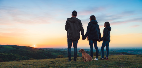 Family with dog embracing while standing on the hill