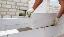 A Worker Lays Foam Concrete Bricks In A House Under Construction