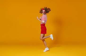 Wall Mural - concept happy emotional young woman in red  jumping   on yellow background