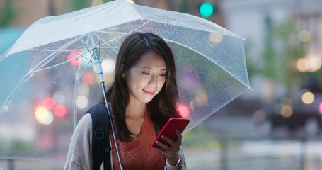 Sticker - Woman use of smart phone and hold with umbrella in the evening