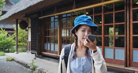 Poster - Woman send audio message on cellphone with the background of the Japanese wooden house