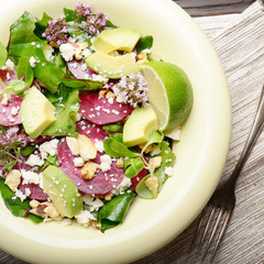 Wall Mural - Top view at mediterranean roasted beet salad with avocado walnuts feta cheese oregano and mash leaves on dinner table