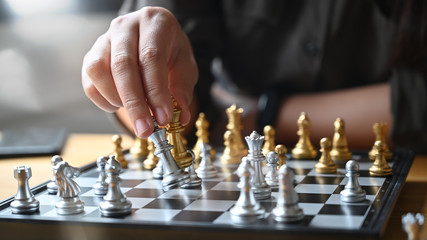 Wall Mural - Strategy or leadership concept, Hand of business moving chess figure in competition success with closeup shot.