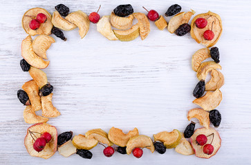 Wall Mural - autumn background, frame of dried fruits with rose hips dried prunes on a white wooden Board, dried apples, pieces