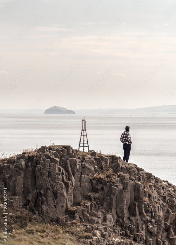 Girl on the top of a hill looking to a island with vintage clothes  - obrazy, fototapety, plakaty 