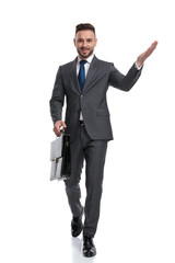 Wall Mural - happy young businessman walking and welcoming while holding suitcase