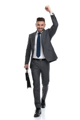 Wall Mural - ecstatic young businessman walking with suitcase and celebrates success