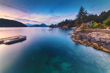 Brilliant sunset rocky beach scenes at sunset with mountains, sky and clouds lit up in early autumn.  Pacific North West Bowen Island British Columbia Canada close to Vancouver.