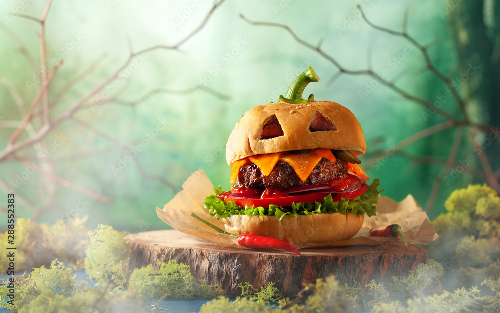 Halloween party burger in shape of scary pumpkin on natural wooden