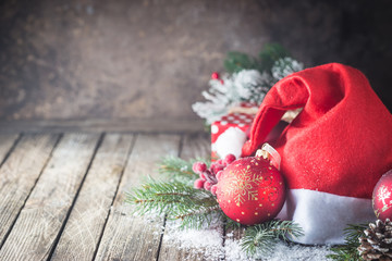 Christmas background with christmas balls, gift, Santa hat and snow on a wooden background