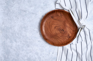 Wall Mural - The brown wooden plate on a towel, on blue table, top view